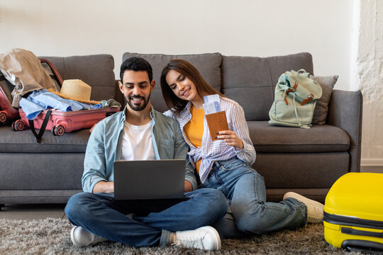 Loving young couple planning trip after quarantine having tickets online reservation, using laptop and booking hotel