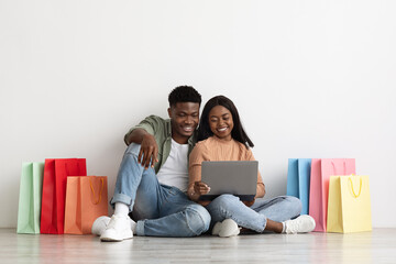 Beautiful black lovers using notebook, shopping online