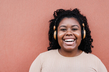 Young african woman listening music with headphones - Focus on face