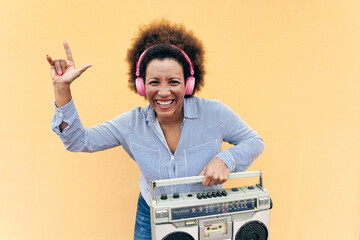 Senior african woman listening music in boombox vintage stereo - Focus on face