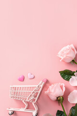 Valentine's Day shopping design concept background with pink rose flower and cart on pink...