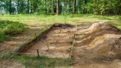 Archaeological excavation in a forest. A large plundering pit dug by archaeologist at an archaeological site.