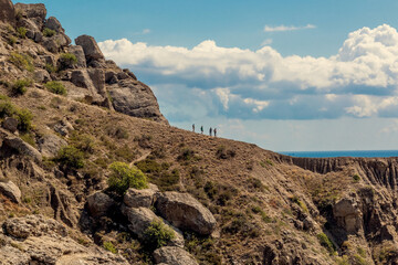 Seascape of the mountains and the sea. Tourists go down the mountainside