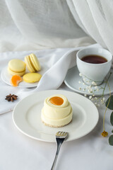 Minimalistic mini cake with white and yellow glaze and cup of tea on the table