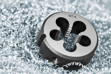 Close-up of steel solid threading die on metal swarf background. Round metric tool to precise...