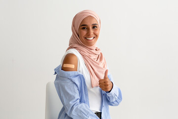 Vaccinated Muslim Woman Showing Arm With Adhesive Bandage And Gesturing Thumb Up