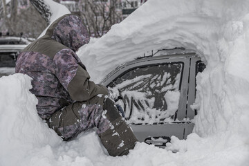 pensive man near a snow-covered car.Car covered with snow after a heavy snow storm
