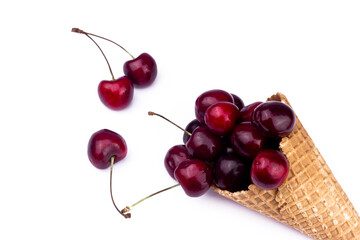 Fresh red cherries in waffle cone. Ice cream cone with ripe sweet cherry on white background with copy space. Summer creative concept flat lay. Top view.