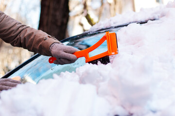 Woman removing snow from car windshield