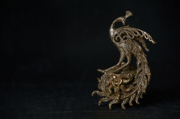 Golden Christmas tree toy in the form of a firebird on a dark background