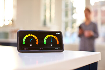 Smart Energy Meter In Kitchen Measuring Domestic Electricity And Gas Use With Figure In Background