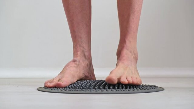 Adult mature man is trampling his feet on orthopedic massage mat designed for acupressure of the feet.Close-up. Effects on reflexogenic zones.Prevention of diseases.The concept of alternative medicine