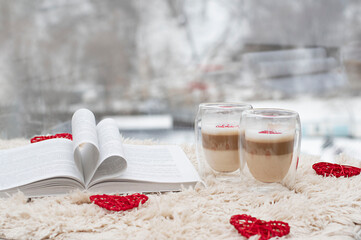 two cups of latte and a book on the background of the window