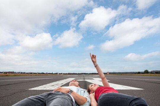 Happy couple on airport runway with plane landing