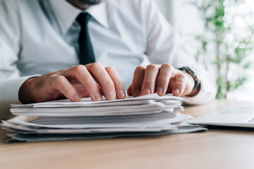 Paperwork workload, businessman with stack of reports for reviewing on office desk