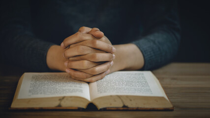 Naklejka premium Christian life crisis prayer to god. Women Pray for god blessing to wishing have a better life. Hands praying to god with the bible. believe in goodness. Holding hands in prayer on a wooden table.