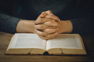Naklejka premium Christian life crisis prayer to god. Women Pray for god blessing to wishing have a better life. Hands praying to god with the bible. believe in goodness. Holding hands in prayer on a wooden table.