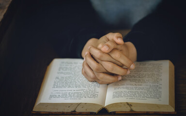 Naklejka premium Christian life crisis prayer to god. Women Pray for god blessing to wishing have a better life. Hands praying to god with the bible. believe in goodness. Holding hands in prayer on a wooden table.