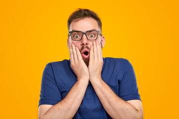 Amazed man touching cheeks in studio