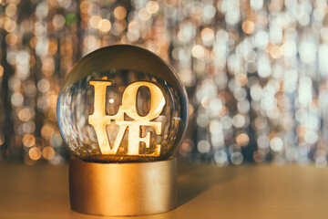 Valentine's day background. Glitter globe with word LOVE on the golden shining bokeh background....
