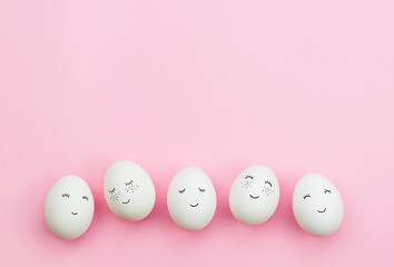 Easter eggs with cute faces painted on a delicate pink background. The concept of the Easter holiday. Top view.