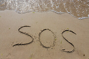 The inscription on the sand at the beach sos