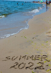 The inscription on the sand Summer symbolizes a summer 2022 vacation at the sea