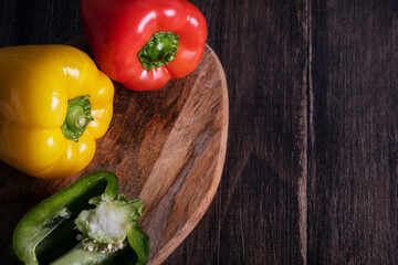 Fresh red, yellow and green peppers on wooden table, horizontal.