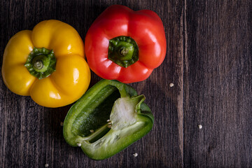 Fresh red, yellow and green peppers on wooden table, horizontal.