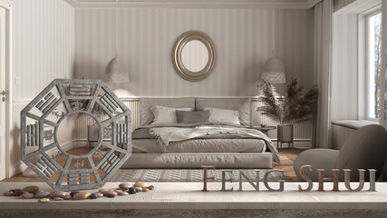 Wooden vintage table shelf with ba gua and 3d letters making the word feng shui over classic bedroom with wallpaper and woodwork, double bed, zen concept interior design