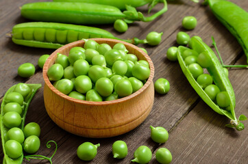 Fresh green peas in wooden bowl