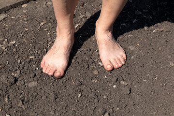 Barefoot woman stands on the raw soil with copy sace for your text