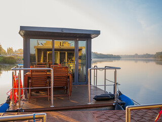 houseboat on a river in a early sunny morning. floating house is a pleasant place for rent for weekend