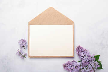 Flowers composition. Envelope, sheet of paper and lilac flowers and on stone background. Template for your invitation or greeting card. Flat lay, top view