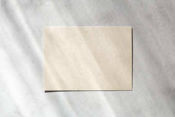 Blank paper sheet cards with sunlight shadows on stone background. Mockup scene with contrasting shadows