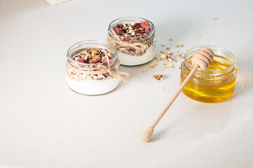 Homemade granola parfait. Quick healthy breakfast greek yogurt, honey, granola with dried berries and nuts in glass jar on stone table. Copy space, selective focus.