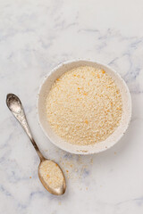 Panko Japanese crispy breadcrumbs in a white plate on a marble background close-up. A crumb for cooking . Selective Focus, top view, copy space