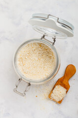 Panko Japanese crispy breadcrumbs in a glass jar on a marble background close-up. A crumb for cooking . Selective Focus, top view, copy space