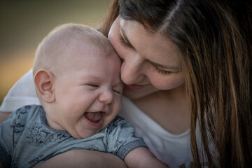 Niño bebé riendo, mirando y sonriendo con su mamá