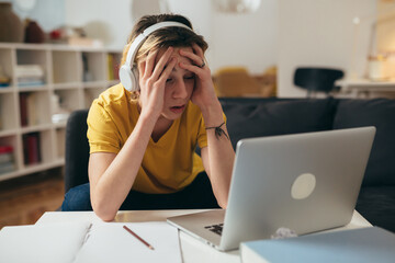teenager boy having online class from home. he is desperate