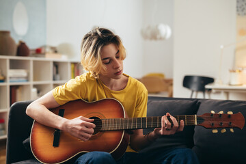 teenager boy playing acoustic guitar at home