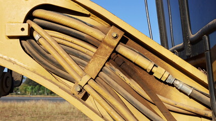 Many old hydraulic hoses. Dirty yellow hydraulic pressure hose system with clamps on the arms of Grader or heavy equipment. Close-up and select focus