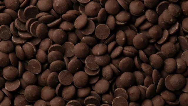 Milk chocolate chips top view rotation. Camera moves away from the object. Confectionery concept. 4K UHD video