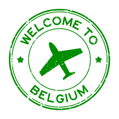 Grunge green welcome to Belgium word with airplane icon round rubber seal stamp on white background
