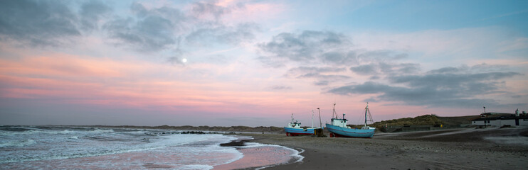 Beach of norre vorupor, denmark, sunset over old fishing boats