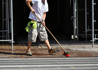 Man is cleaning the street with a broom