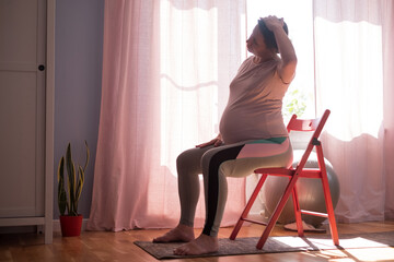 Pregnant woman on fitness mat, training at home