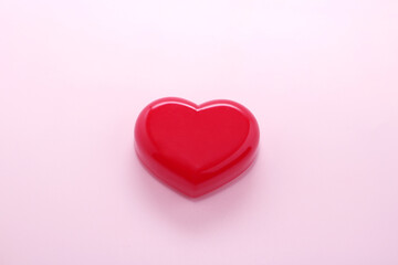 A red heart in the center on a light pink background.