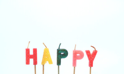 A candle with the word " HAPPY " in bright colors against a white background.