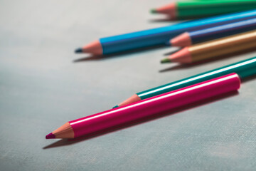 Row of colored pencils on gray canvas.